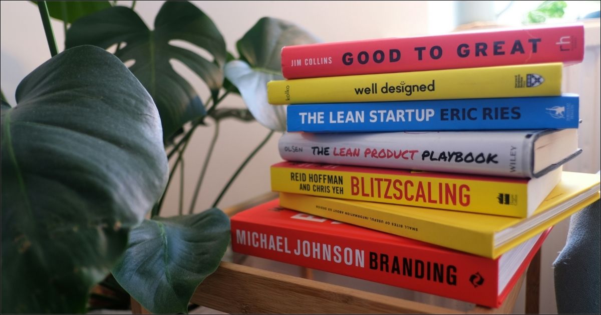 A stack of books about work management methods on an end table beside a plant.